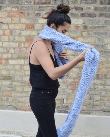 Woman wrapping pale blue scarf around neck