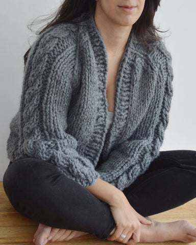 Woman seated wearing grey cable knit cardigan
