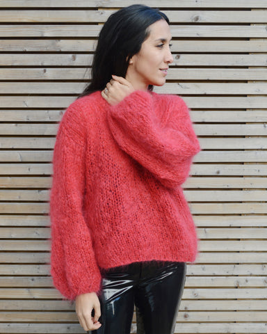 Woman standing against wooden fence wearing red mohair sweater