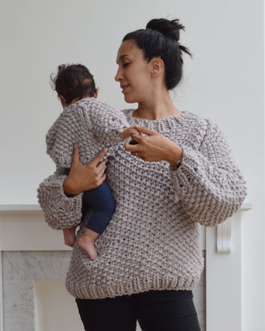 Woman and baby wearing matching lilac chunky knit sweaters against light background