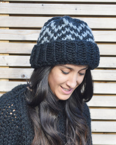 Woman with brown hair wearing grey and black zigzag knitted beanie